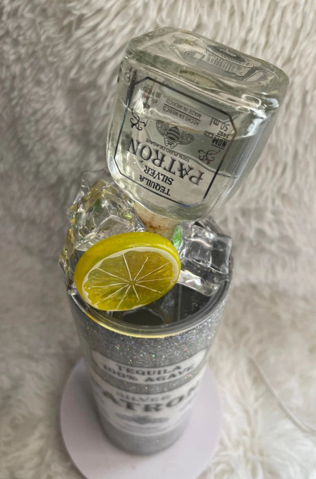 Tequila bottle with a lemon slice on a textured surface