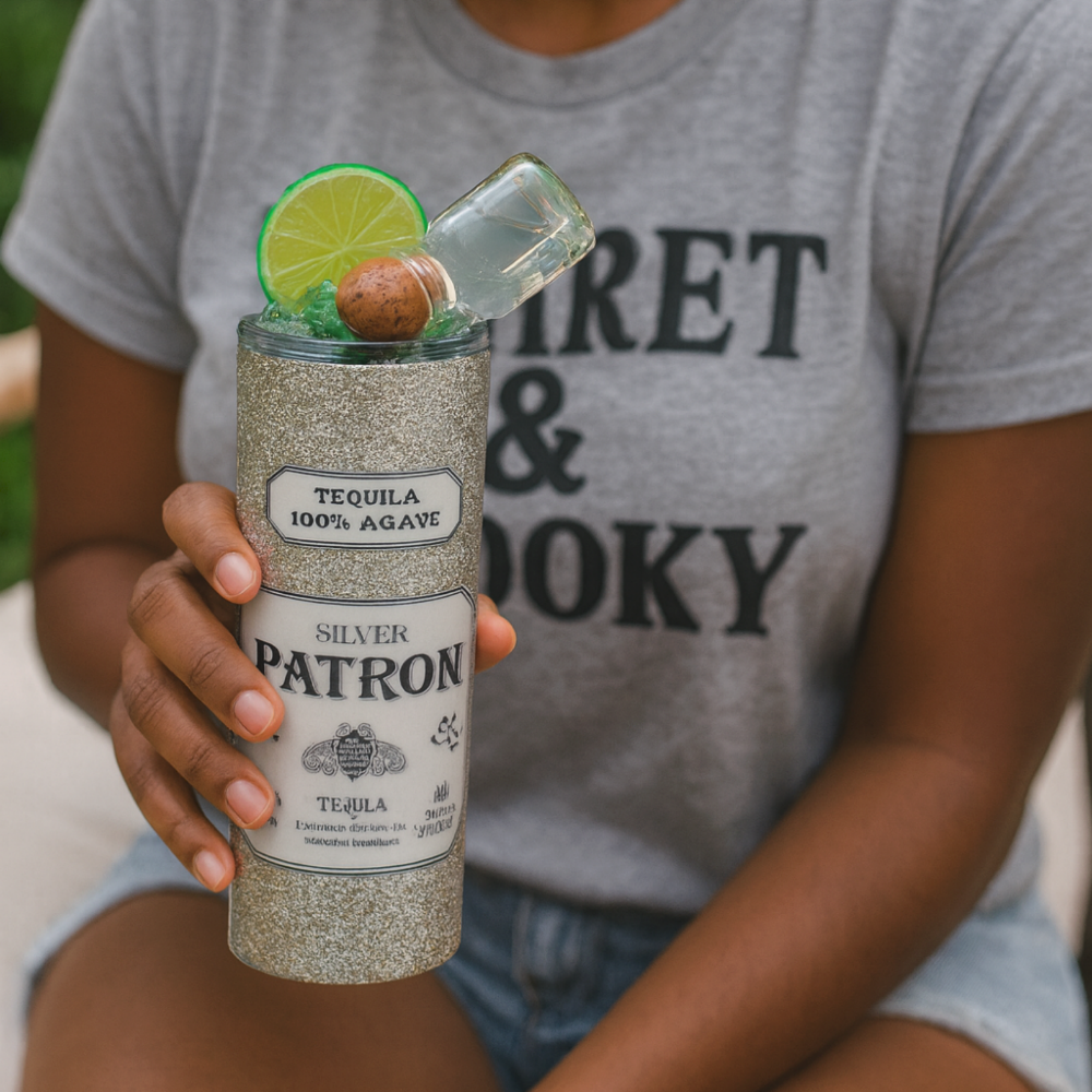 Young woman smiling and holding a glittery custom Silver Patrón tumbler with faux ice, lime, and mini bottle topper; outdoor lifestyle scene promoting handmade drinkware by Lavish Designs by Jelisha.