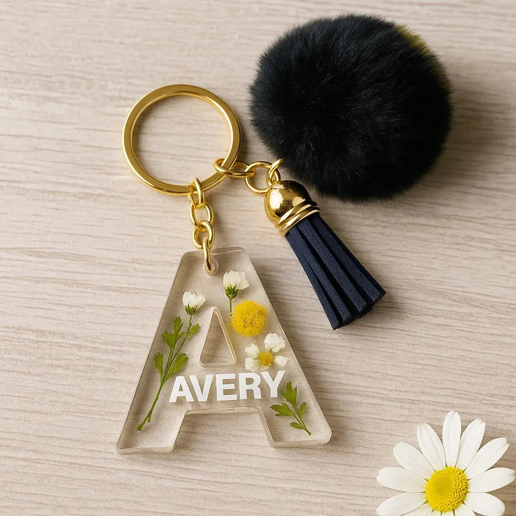 Keychain with floral 'A' and tassel on a wooden surface