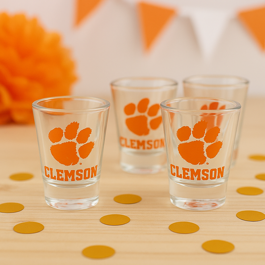 Clemson-themed shot glasses on a wooden surface with confetti.